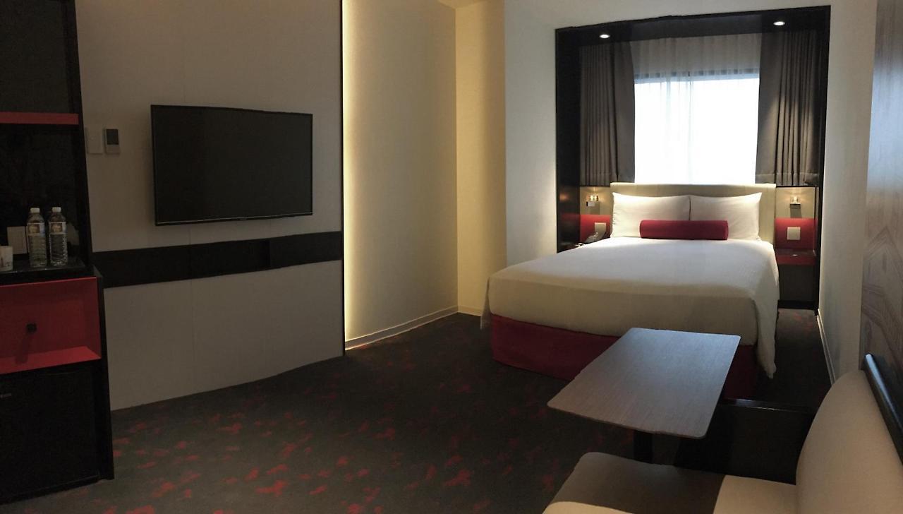 臺北 台北凯达大饭店酒店 外观 照片 The photo shows a modern hotel room layout. The space features a comfortable bed with white linens and a red accent pillow. There's a flat-screen TV mounted on the wall opposite the bed, along with a sleek, minimalist design that includes a small tab