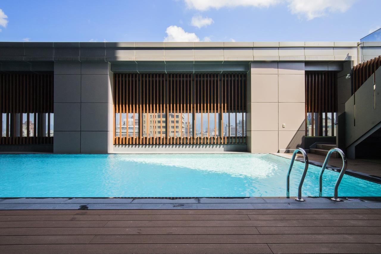 臺北 台北凯达大饭店酒店 外观 照片 The photo depicts a modern rooftop swimming pool with clear blue water. The pool area is surrounded by a sleek, contemporary architectural design, featuring large windows and wooden slats that provide both an aesthetic appeal and some shade. In the b