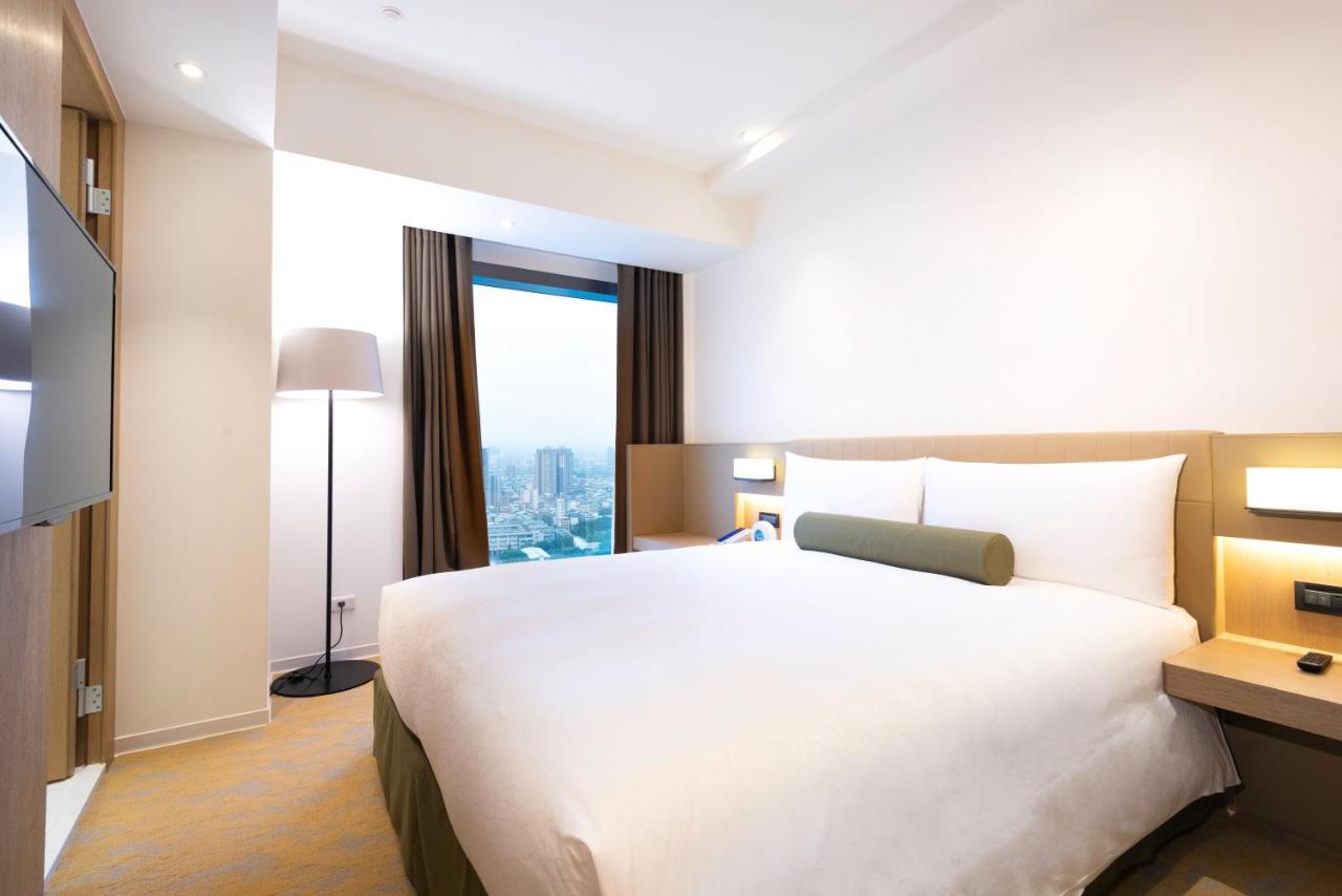 臺北 台北凯达大饭店酒店 外观 照片 The photo shows a modern hotel room with a simple and clean design. It features a double bed with white bedding and a green accent pillow. There are two large windows with dark curtains, allowing natural light to enter. A floor lamp stands beside the