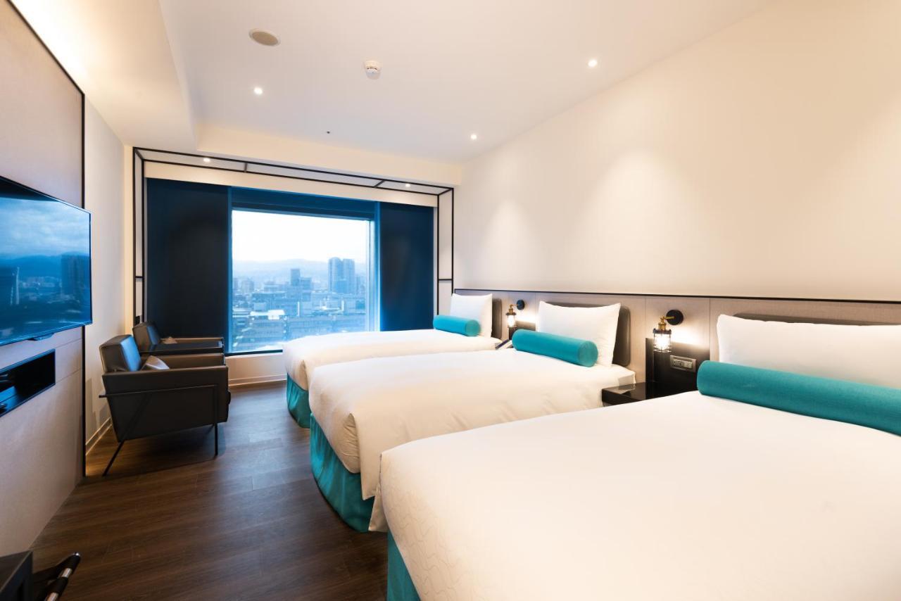 臺北 台北凯达大饭店酒店 外观 照片 The photo shows a modern hotel room featuring two beds with white bedding and light blue accents. The room has sleek, contemporary design elements, including a wall-mounted television and a large window that offers a view of the outside, likely a cit