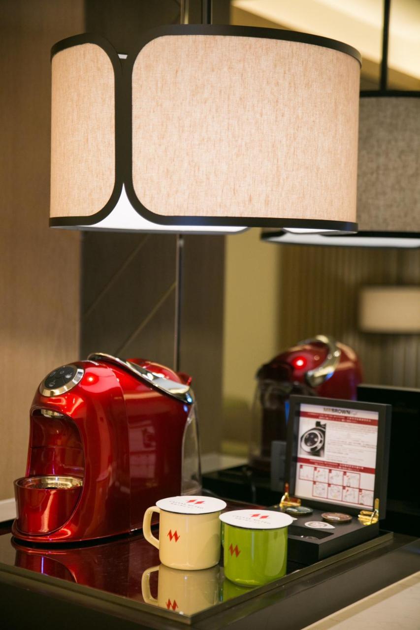 臺北 台北凯达大饭店酒店 外观 照片 The photo shows a red kettle sitting on a countertop. Above it, there is a stylish lamp with a fabric shade that has a light color and a black trim. The background appears to have modern decor, with another light source visible. There seems to be a s