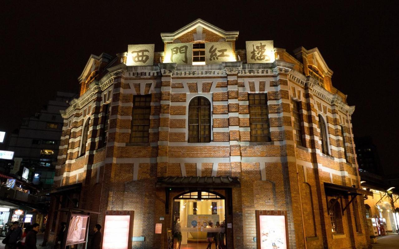 臺北 台北凯达大饭店酒店 外观 照片 The photo shows a historical building illuminated at night. It features a distinct architectural style with a mix of brick and stone materials, characterized by a rounded structure and multiple windows. The front of the building is adorned with large