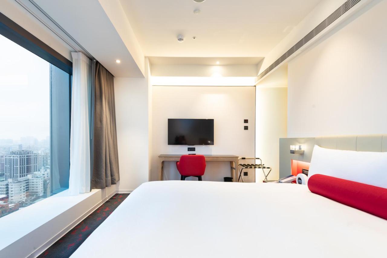 臺北 台北凯达大饭店酒店 外观 照片 The photo shows a modern hotel room featuring a large bed with a white duvet. There is a window with sheer curtains that allows natural light to enter, providing a view of the outside. A flat-screen television is mounted on the wall opposite the bed.