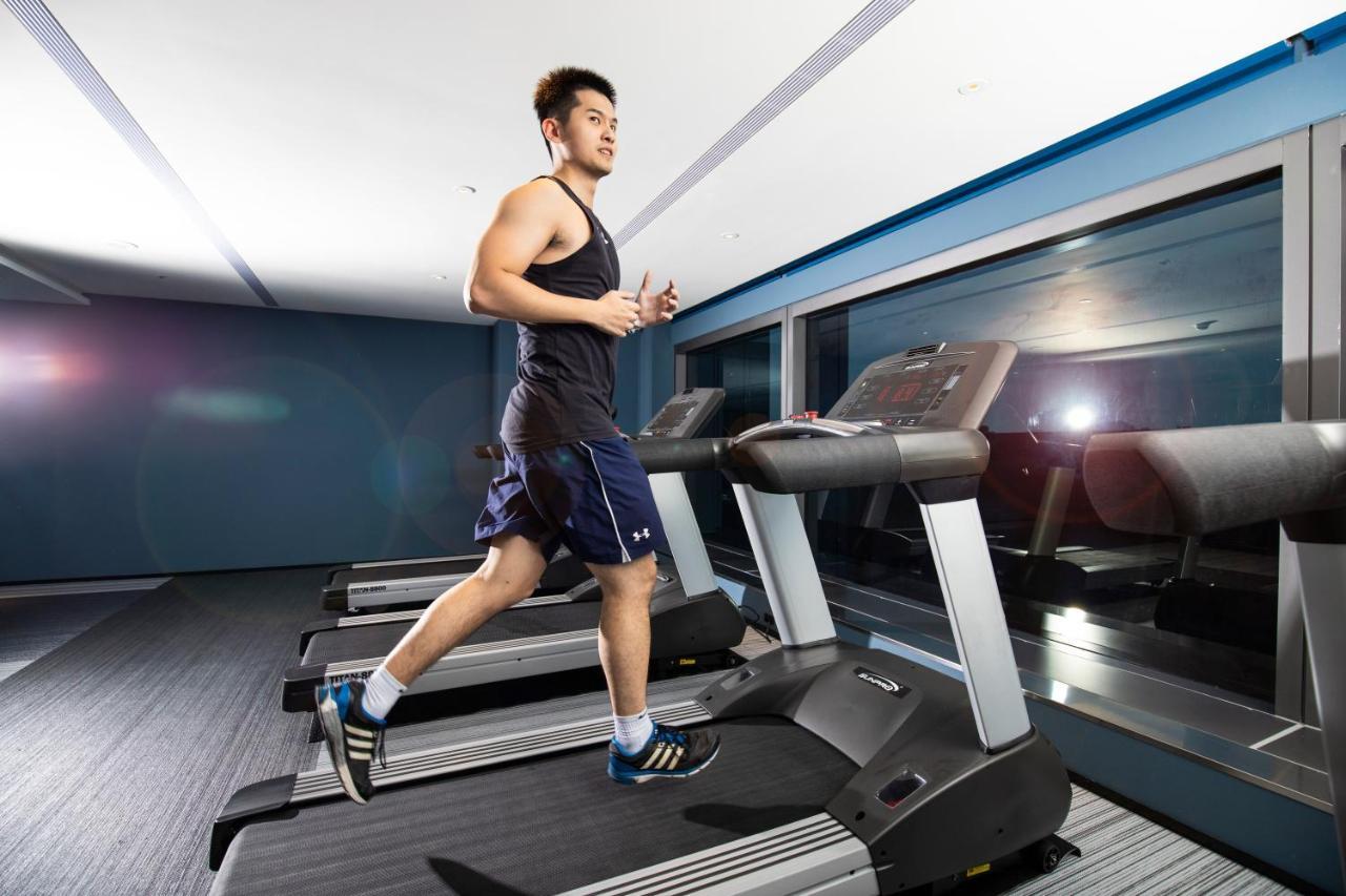 臺北 台北凯达大饭店酒店 外观 照片 The photo shows a young man jogging on a treadmill in a gym or fitness facility. He is dressed in a sleeveless athletic top and shorts. The gym has modern equipment, and large windows are visible, likely allowing natural light to enter the space. The