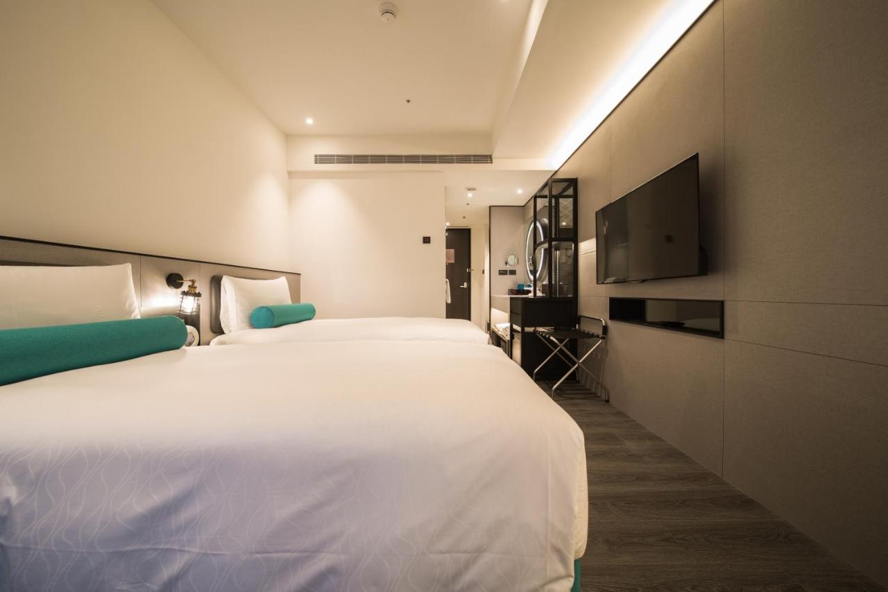 臺北 台北凯达大饭店酒店 外观 照片 The photo shows a modern hotel room featuring two beds with white linens and teal accents. The walls are a light, neutral color, contributing to a clean and contemporary aesthetic. There is a minimalist design, with a mounted flat-screen TV on one wa